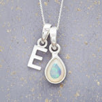 Sterling Silver necklace with 'E' initial pendant and white teardrop October Birthstone Opal gemstone on a grey background.