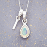 sterlingSilver necklace with a 'I' initial and a teardrop-shaped opal pendant on a textured grey background