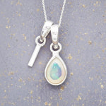 Sterling Silver necklace with 'I' initial pendant and white teardrop October Birthstone Opal gemstone on a grey background.