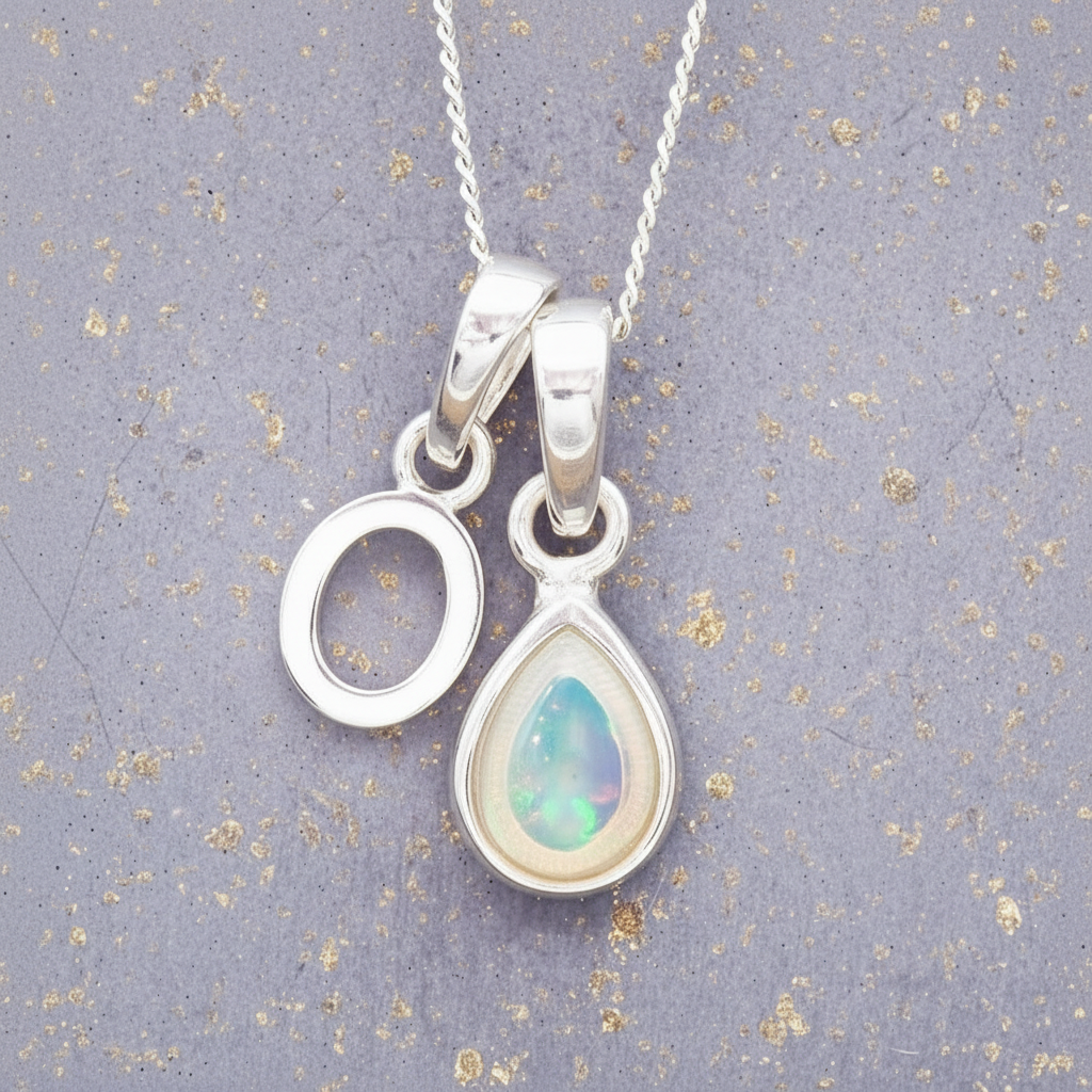 Sterling Silver 'O' initial pendant with a teardrop-shaped october birthstone opal stone on a grey background