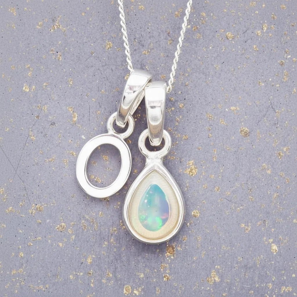 Sterling Silver necklace with 'O' initial pendant and white teardrop October Birthstone Opal gemstone on a grey background.