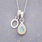 Sterling Silver necklace with 'O' initial pendant and white teardrop October Birthstone Opal gemstone on a grey background.