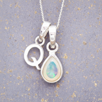 Sterling Silver 'Q' initial pendant with a teardrop-shaped opal stone on a textured gray background