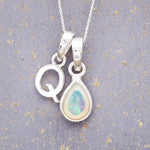 Sterling Silver necklace with 'Q' initial pendant and white teardrop October Birthstone Opal gemstone on a grey background.