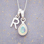 Sterling Silver necklace with 'R' initial pendant and white teardrop October Birthstone Opal gemstone on a grey background.
