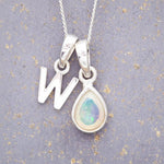 Sterling Silver necklace with 'W' initial pendant and white teardrop October Birthstone Opal gemstone on a grey background.