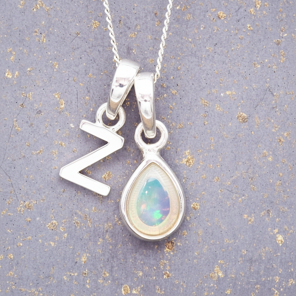 Sterling Silver necklace with a teardrop-shaped october birthstone opal pendant and a 'Z' initial pendant on a textured grey background
