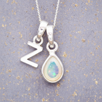 Sterling Silver necklace with a teardrop-shaped october birthstone opal pendant and a 'Z' initial pendant on a textured grey background