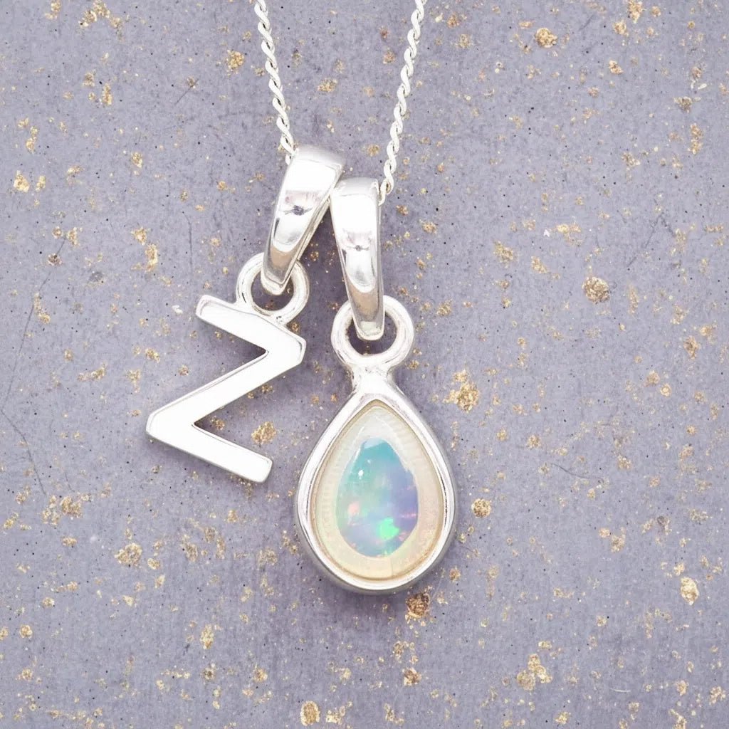 Sterling Silver necklace with 'Z initial pendant and white teardrop October Birthstone Opal gemstone on a grey background.