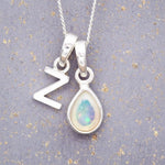 Sterling Silver necklace with 'Z initial pendant and white teardrop October Birthstone Opal gemstone on a grey background.