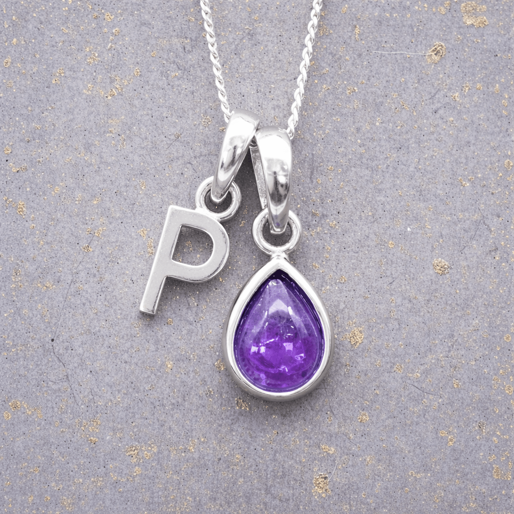 sterling Silver necklace with a purple teardrop february birthstone amethyst pendant and letter 'P' charm on a textured grey background.