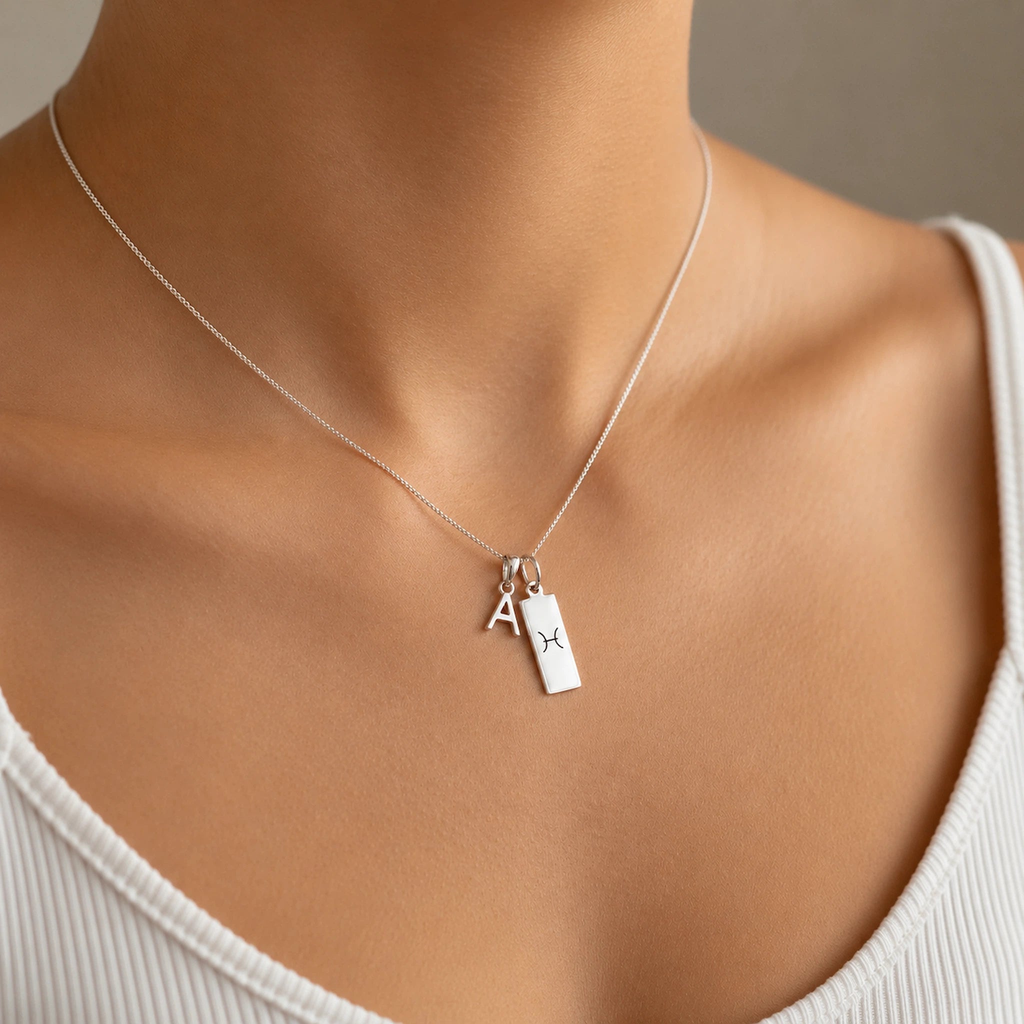 model wearing a Sterling Silver Double pendant necklace with a letter pendant and a rectangle pendant with the pisces zodiac glyph.