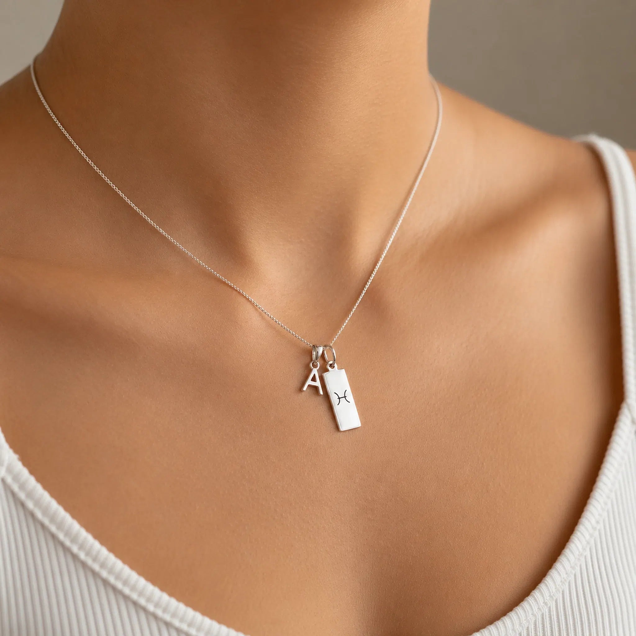 model wearing a Sterling Silver Double pendant necklace with a letter pendant and a rectangle pendant with the pisces zodiac glyph.