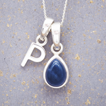 sterling Silver necklace with 'P' pendant and blue teardrop september birthstone sapphire pendant on a textured grey background