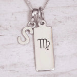 sterling Silver double pendant necklace with a rectangle pendant with the virgo zodiac glyph, and a 'S' initial pendant on a light wooden background