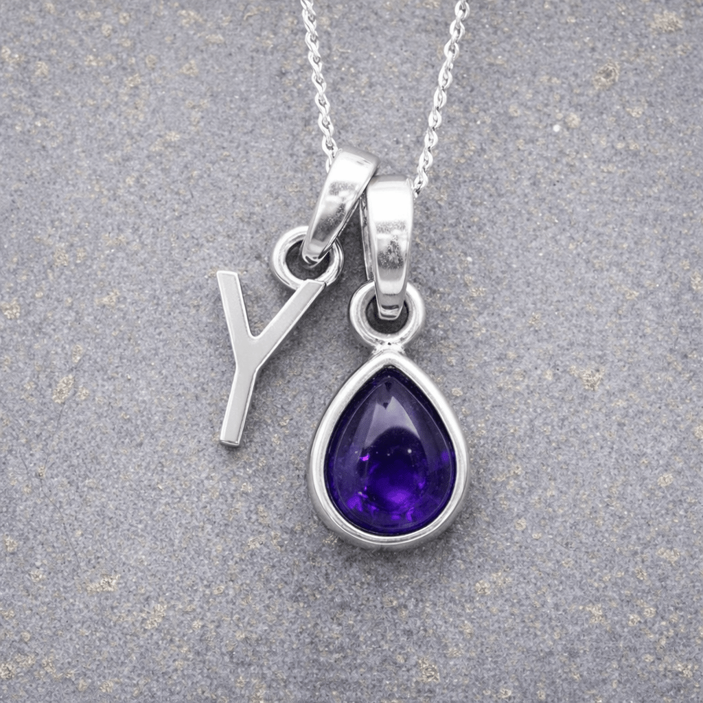 sterling Silver necklace with a 'Y' initial pendant and a purple teardrop february birthstone amethyst pendant on a textured grey background