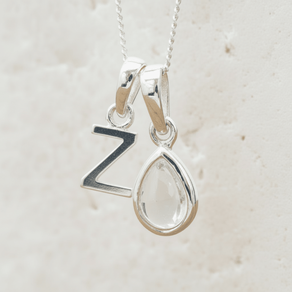 Silver necklace with a teardrop herkimer quartz pendant and a 'Z' initial pendant on a light beige background