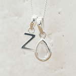 Silver necklace with a teardrop herkimer quartz pendant and a 'Z' initial pendant on a light beige background
