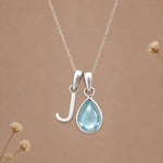 Sterling silver J initial necklace with pale blue March aquamarine in a polished teardrop bezel