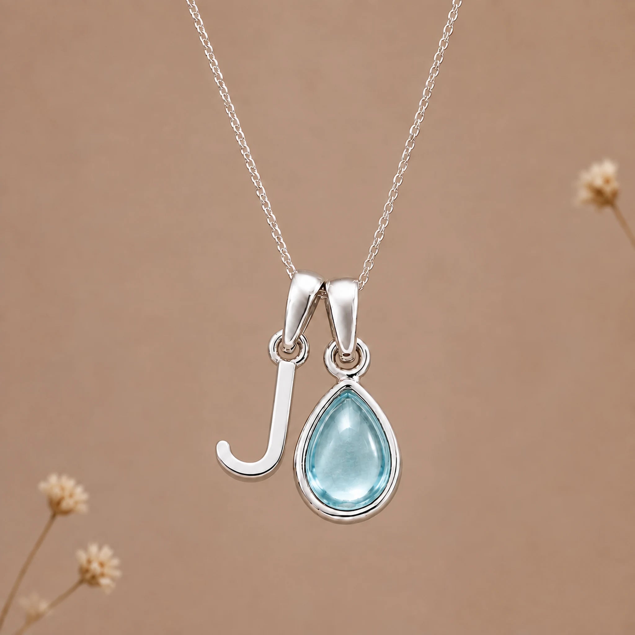 Sterling silver J initial necklace with pale blue March aquamarine in a polished teardrop bezel