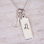 sterling silver initial j leo zodiac star sign pendant necklace against a light wooden background