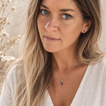 model wearing a sterling silver january birthstone jewellery set of a natural garnet pendant necklace and matching stud garnet earrings