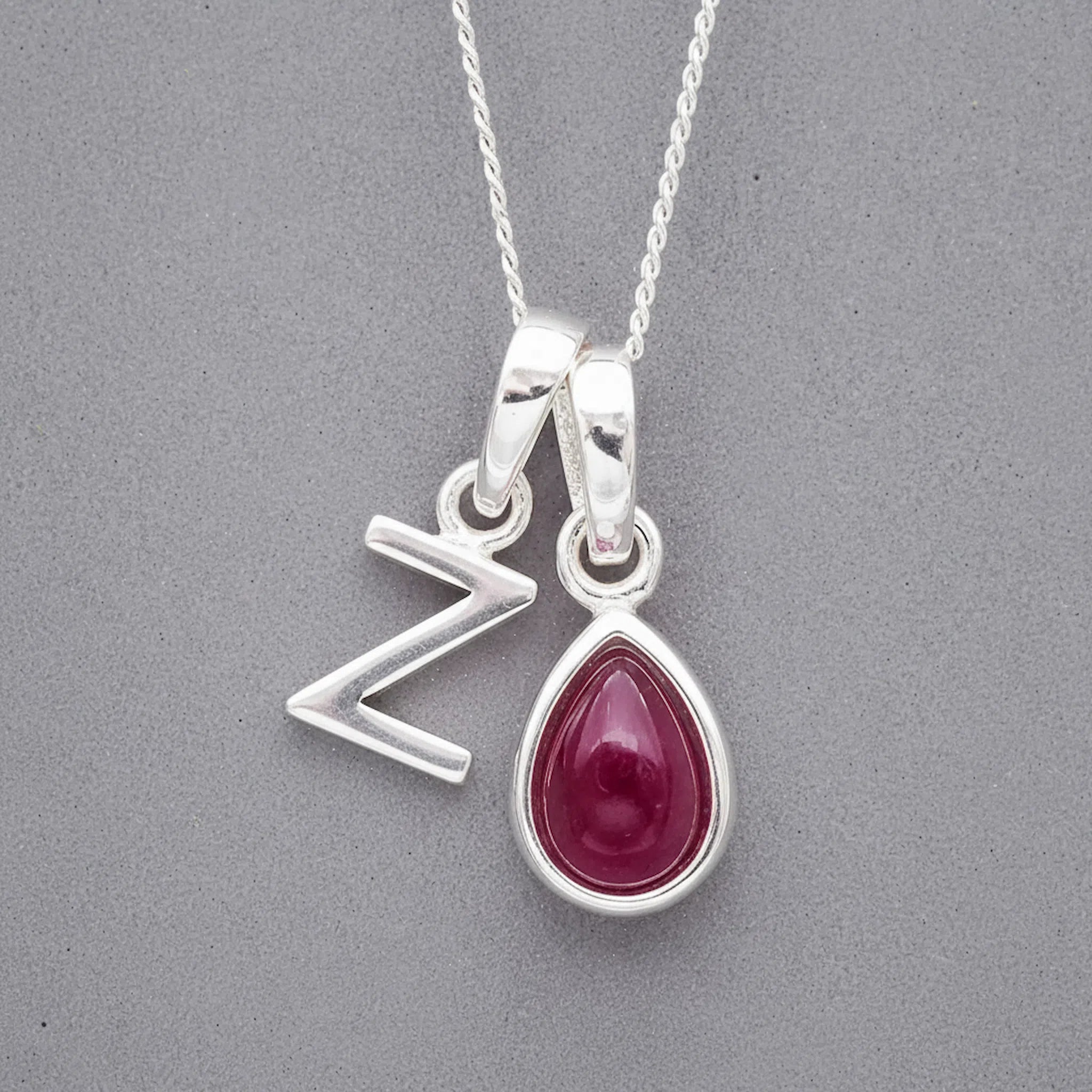 Sterling Silver double pendant necklace with a capital Z pendant and a teardrop-shaped july birthstone ruby gemstone on a grey background