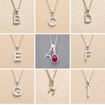 Collection of silver letter pendants A to I on beige and grey backgrounds as personalised initial pendant options for July Birthstone Ruby Necklace.