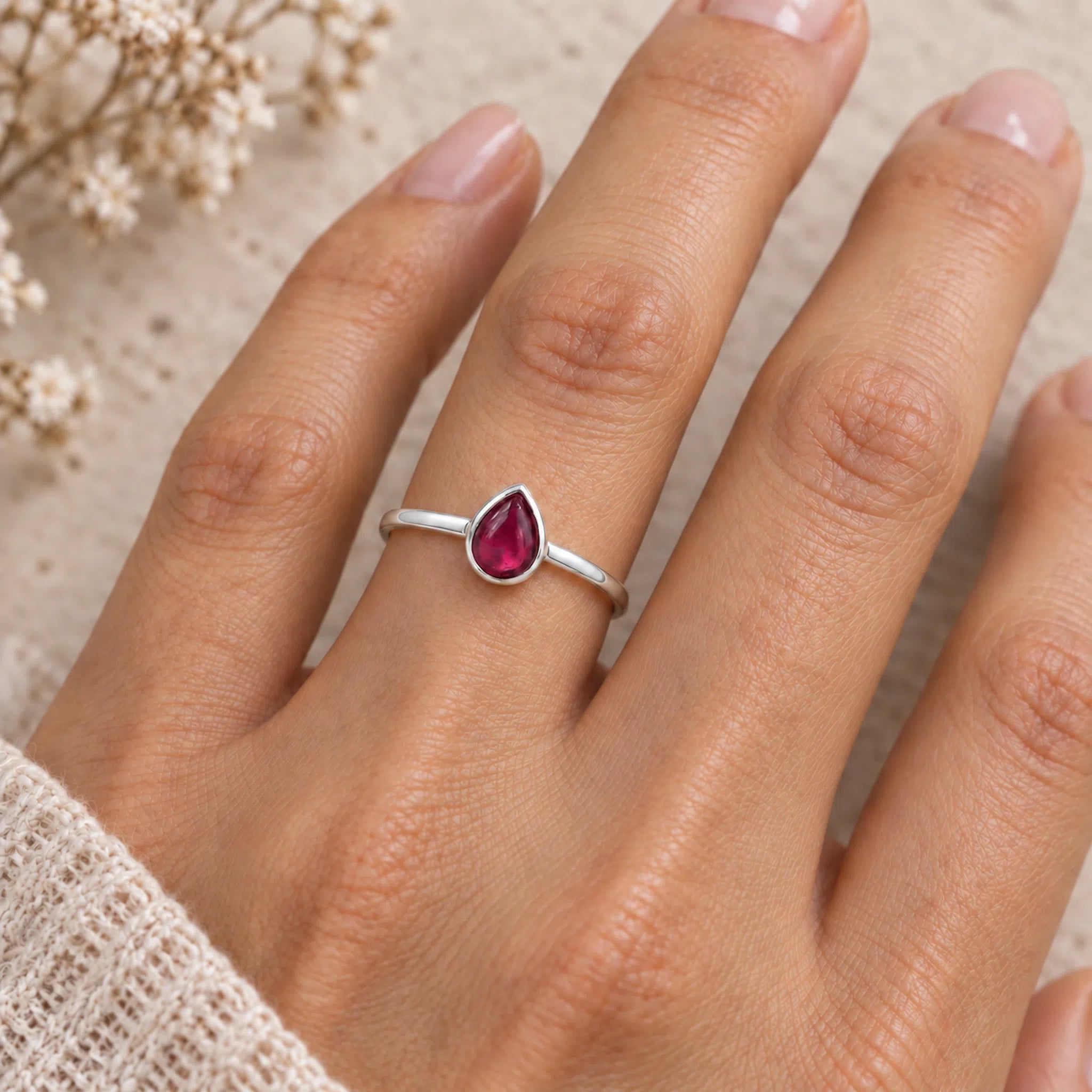 sterling silver july birthstone ring featuring a pear-shaped cabochon bezel-set natural ruby being worn