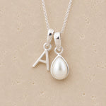 Sterling Silver double pendant necklace with a teardrop-shaped June birthstone Mother of Pearl pendant and letter 'A' charm on a beige background
