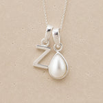 Sterling Silver double pendant necklace with a teardrop-shaped June birthstone Mother of Pearl pendant and letter 'Z' charm on a beige background