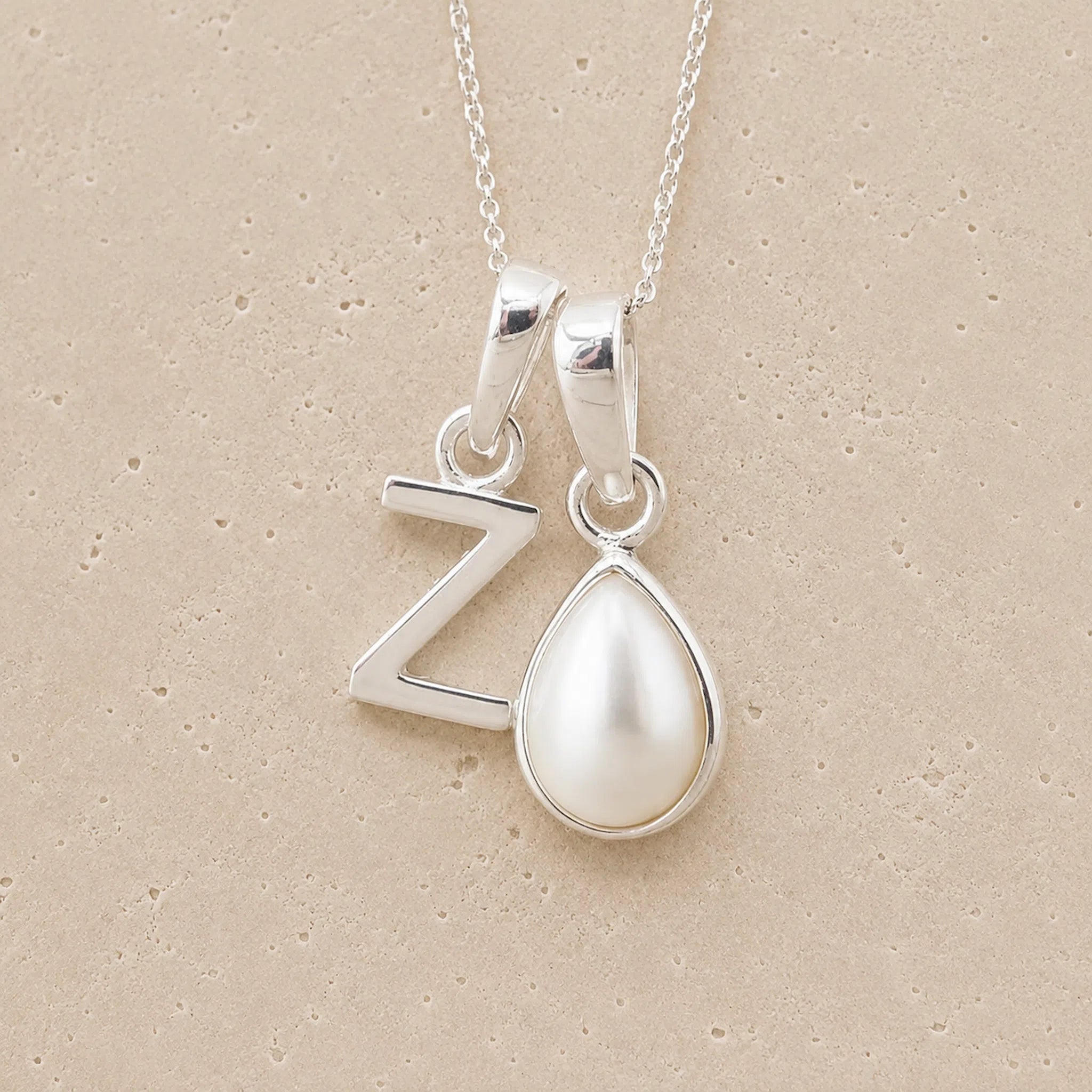 Sterling Silver double pendant necklace with a teardrop-shaped June birthstone Mother of Pearl pendant and letter 'Z' charm on a beige background