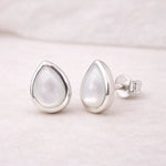 sterling Silver teardrop stud earrings with a light-colored natural pearl gemstone on a soft pink background