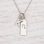 sterling silver initial K pendant and capricorn necklace on a fine silver chain against a light wooden background