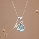 Sterling silver K initial necklace with pale blue March aquamarine in a polished teardrop bezel