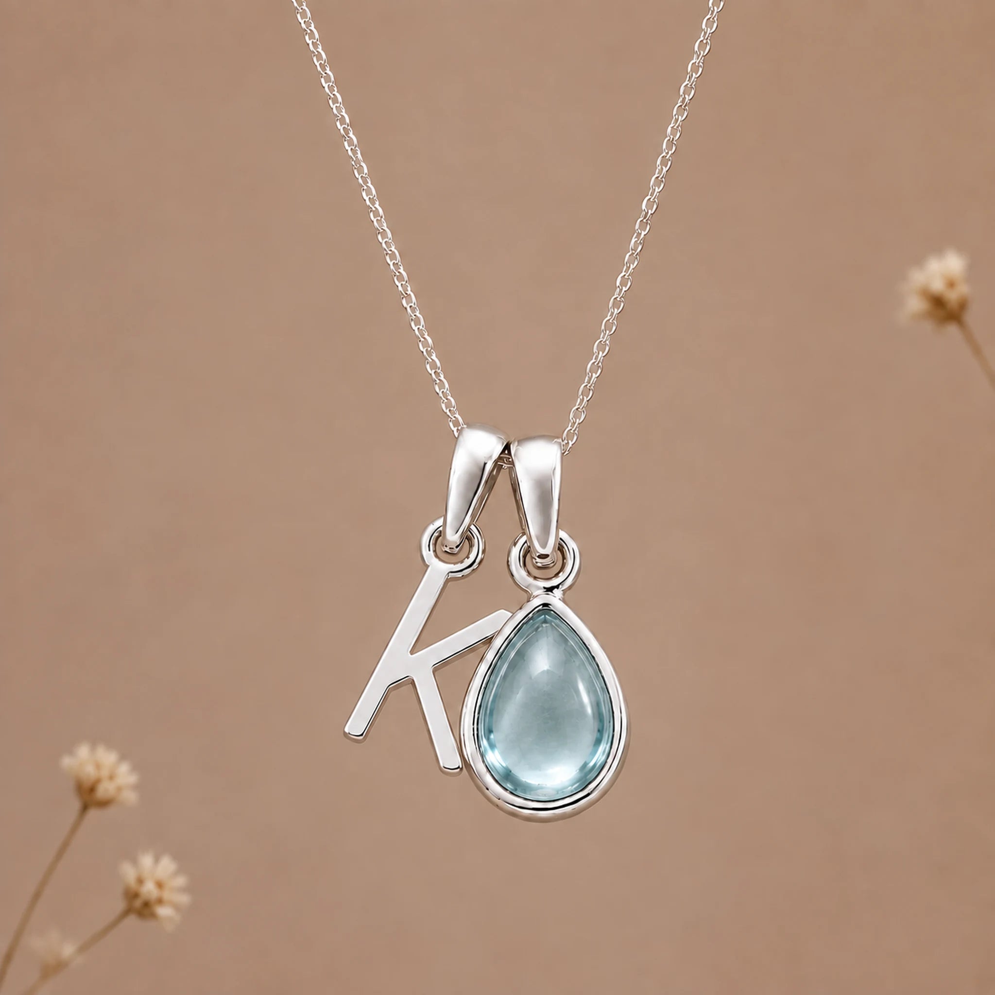 Sterling silver K initial necklace with pale blue March aquamarine in a polished teardrop bezel