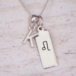 sterling silver initial k leo zodiac star sign pendant necklace against a light wooden background