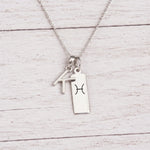 sterling silver K initial Pisces Necklace on a fine silver chain against a light wooden background