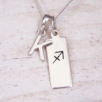 sterling silver initial k sagittarius zodiac star sign pendant necklace against a light wooden background