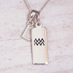 Sterling Silver L Initial and Aquarius Necklace on a fine silver chain against a light wooden background