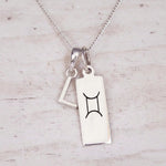 Sterling silver L initial and GeminI Necklace on a fine silver chain on a light wooden background