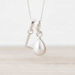 Sterling Silver necklace with a L initial pendant and a teardrop pearl pendant on a light background