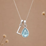 Sterling silver L initial necklace with pale blue March aquamarine in a polished teardrop bezel