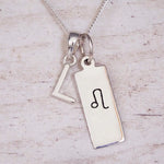sterling silver initial l leo zodiac star sign pendant necklace against a light wooden background