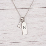 sterling silver L initial Pisces Necklace on a fine silver chain against a light wooden background