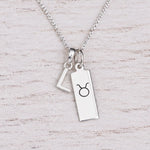 Sterling silver L initial Pendant and Taurus Necklace on a fine silver chain on a light wooden background