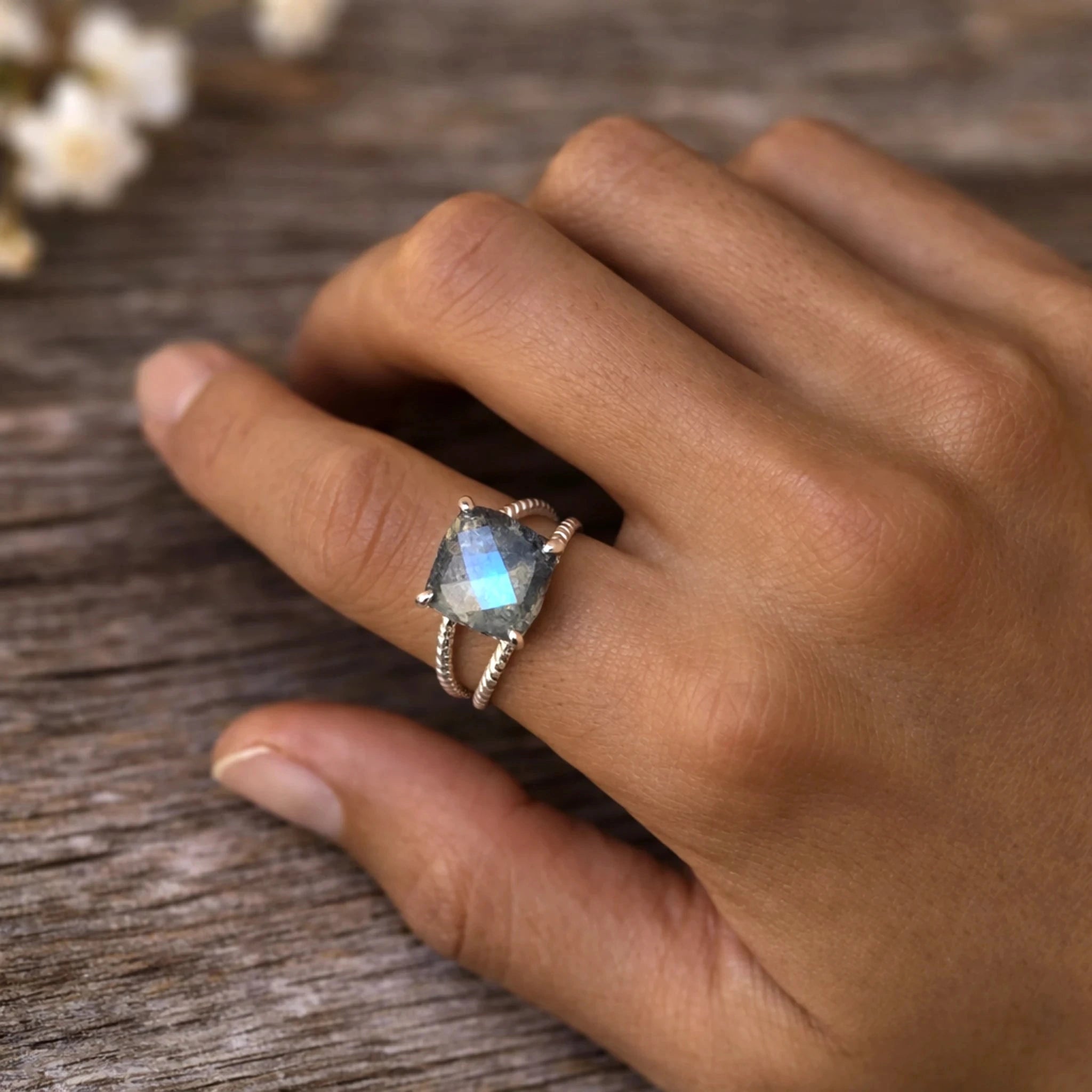Hand wearing the blue labradorite ring on a wooden surface