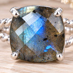 Silver labradorite double twist ring on wood, close-up