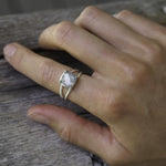 Hand wearing a sterling silver ring with a labradorite on a wooden surface