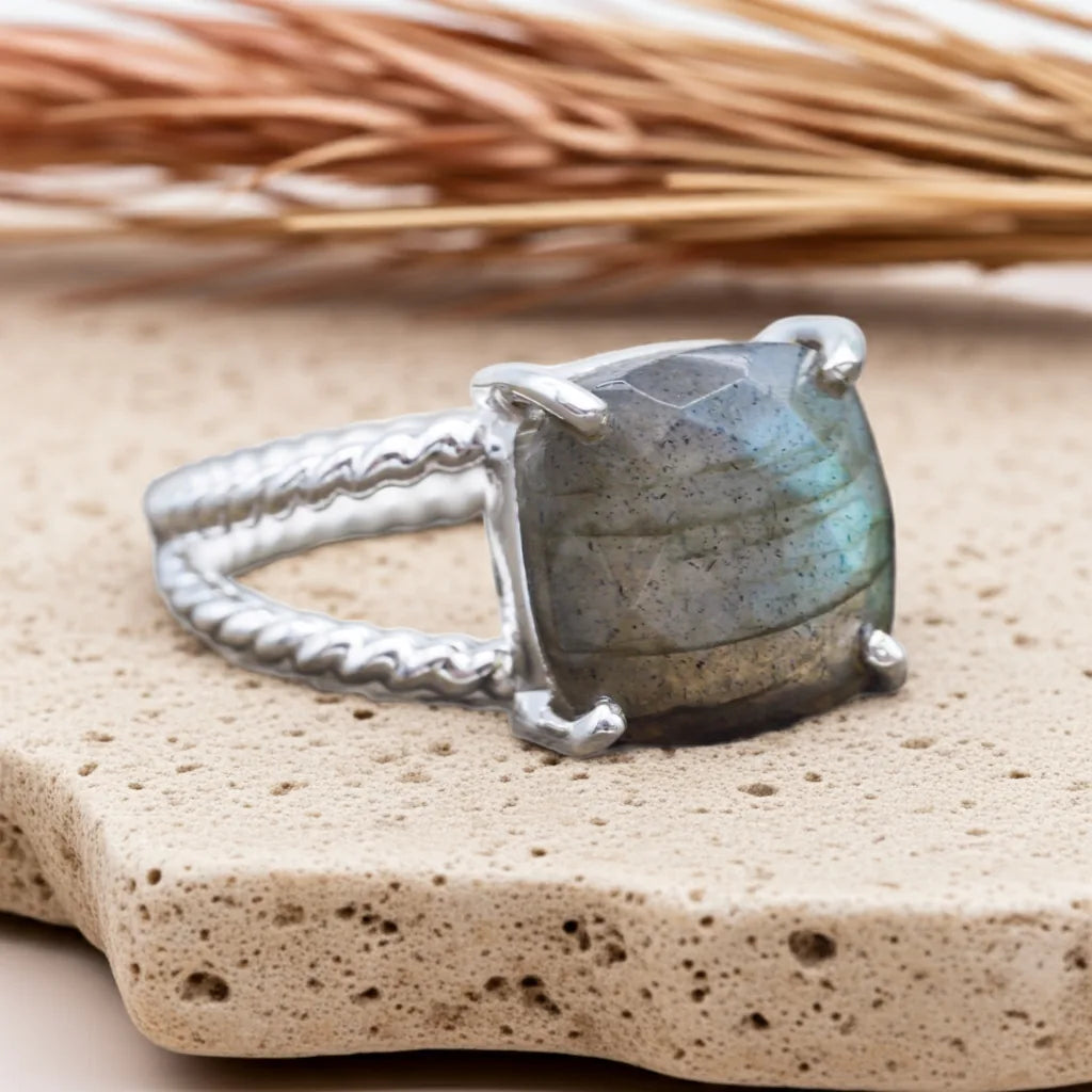 Silver ring with a large labradorite stone on a textured surface